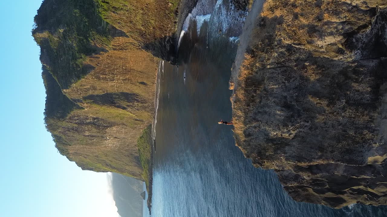 Aerial drone view above beautiful blonde girl walking at Miradouro Do Guindaste, Crane Viewpoint at the coast of Madeira island
