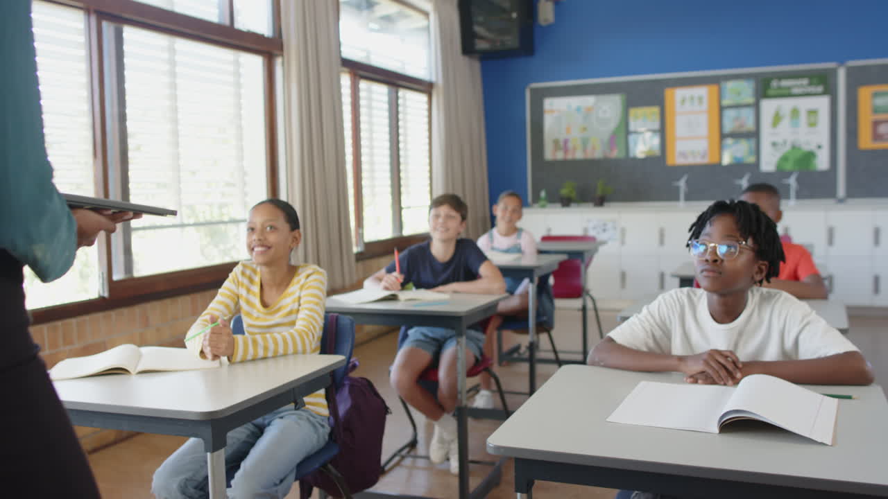 In school classroom, students sitting at desks, listening to teacher attentively