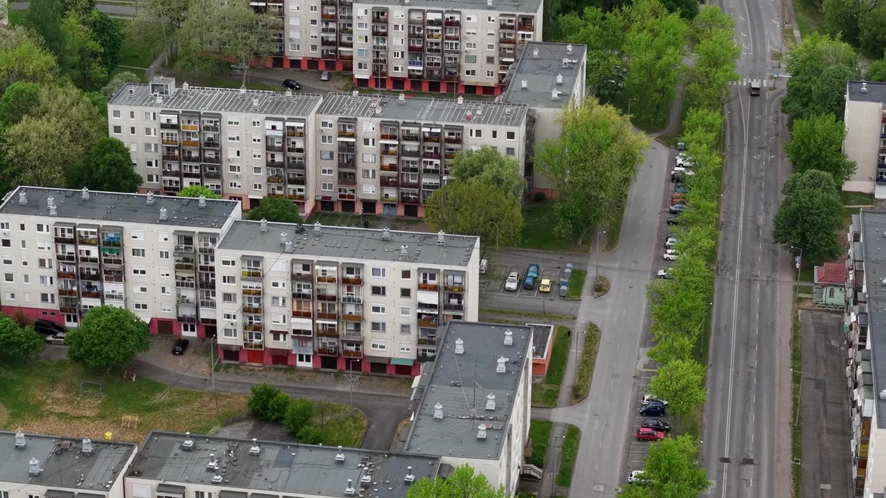 Widok z lotu ptaka ukazuje skupisko betonowych budynków mieszkalnych położonych wzdłuż utwardzonych ulic w zielonej dzielnicy miejskiej
