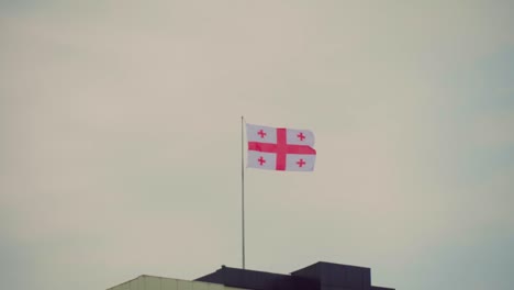 the flag of georgia flies slowly against the background of a clear blue sky, smoothly looping, close-up, perfect for movies, news, digital composition