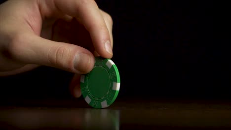 person placing a green poker chip on a table