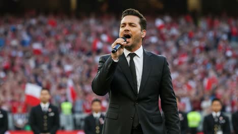 a captivating performance: a solo artist dressed in formal attire singing passionately in front of an enthusiastic crowd filled with flags