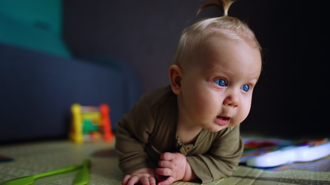 Adorable joyful baby with blond hair and tiny tail on head crawling by the floor. Infant learning to move in space.