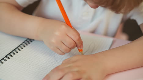 Boy-draws-abstract-picture-with-graphite-pencil-at-desk