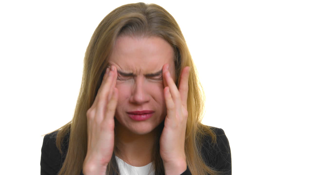 un primer plano de una mujer con dolor de cabeza-migraña, manos a ambos lados de la sien de su cabeza, sobre un fondo de estudio blanco sin costuras