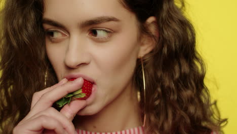 una mujer joven comiendo fresas.