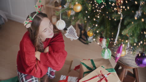 feliz mujer hermosa mirando el árbol de navidad y regalos