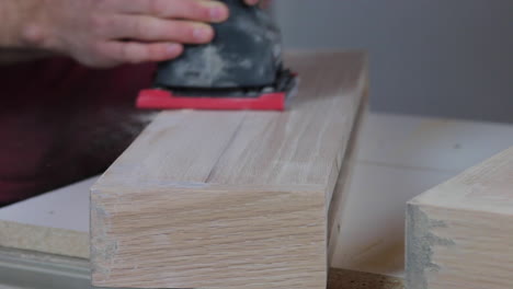 Finish-sanding-the-wood-filler-on-wooden-floating-shelves-in-preparation-to-be-stained-and-hung-in-a-remodeled-bathroom