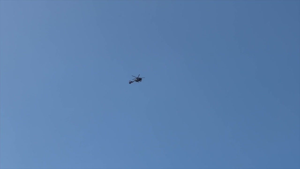 헬리터가 밝은 파란 하늘을 향해 멀리서 떠다니고 있습니다.