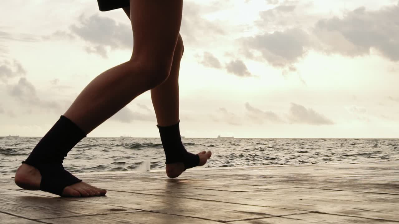 Female boxer's legs moving on during the training. Woman is training by the beach. Close Up on legs. Slow Motion shot