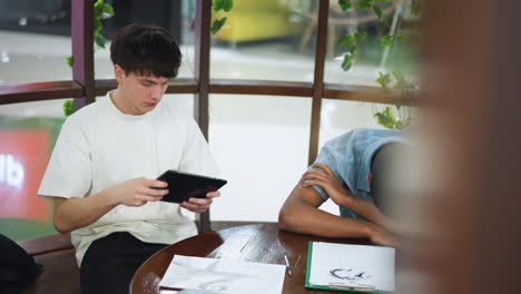 clear shot of modern space with glass walls wooden desk inside young professional sitting using smartphone and tablet multitask in minimalist soft light filled conference showcasing interior designs