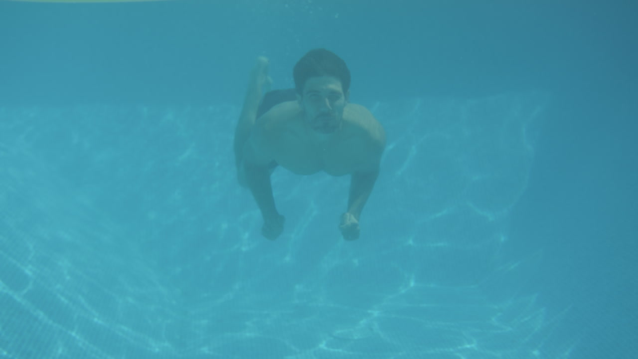 fotografía submarina de un hombre sorprendiendo a una mujer flotando en una cama de aire en una piscina en vacaciones de verano