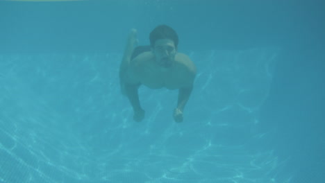 underwater shot of man surprising woman floating on airbed in swimming pool on summer vacation