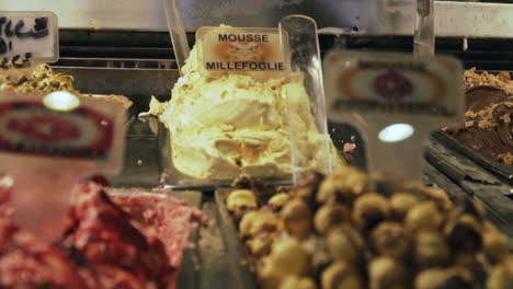 rack focus between gelato flavors in display case in gelateria, slow motion