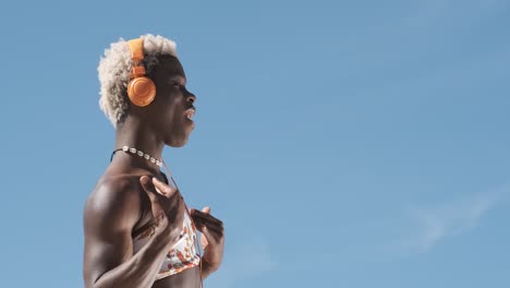 transgender person dancing while listening to music with headphones outdoors.