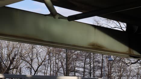 water reflections of the sunlight that are coming from the surface of the lake towards the metal beams of the bridge