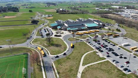 yellow school bus and cars picking up students of high school in american suburb