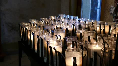 close up of candles burning in church with camera pulling back slowly