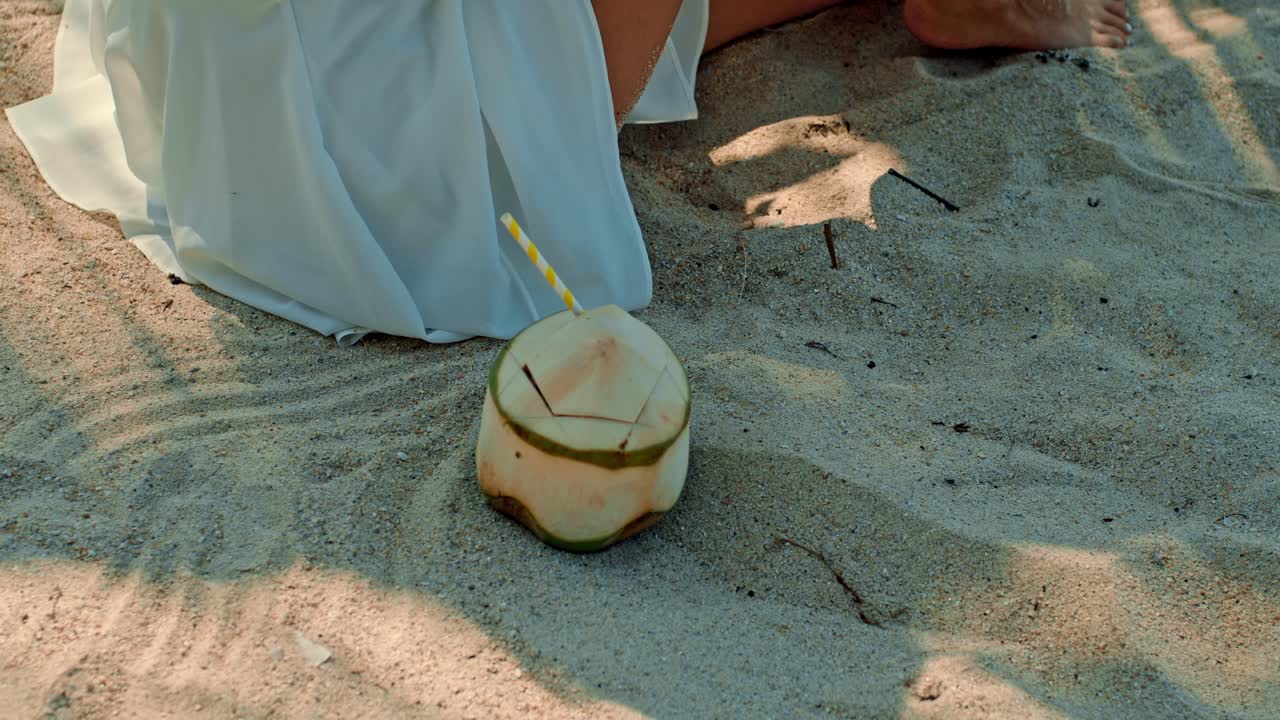 Woman enjoying a coconut on the beach