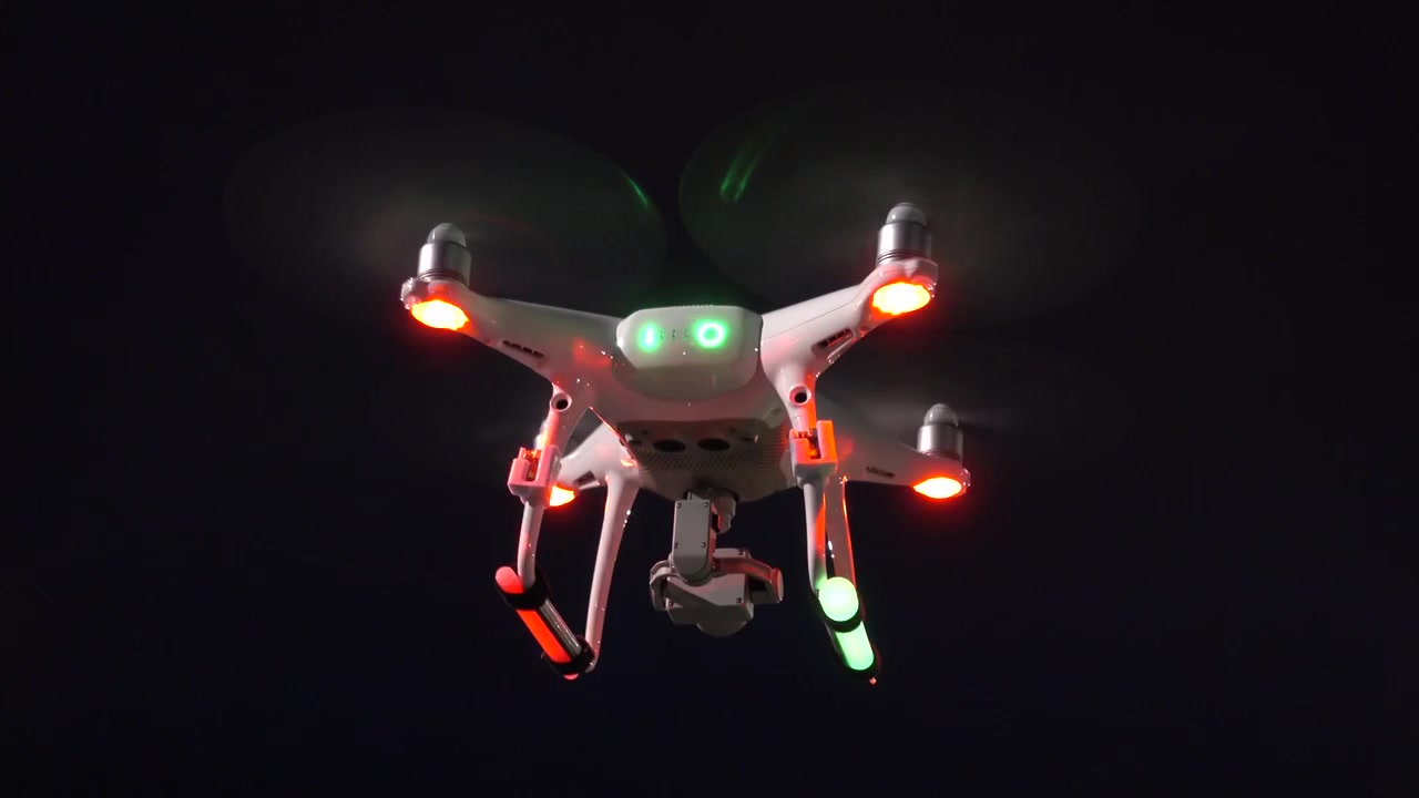 Drone hovering at night with strobes and glow sticks