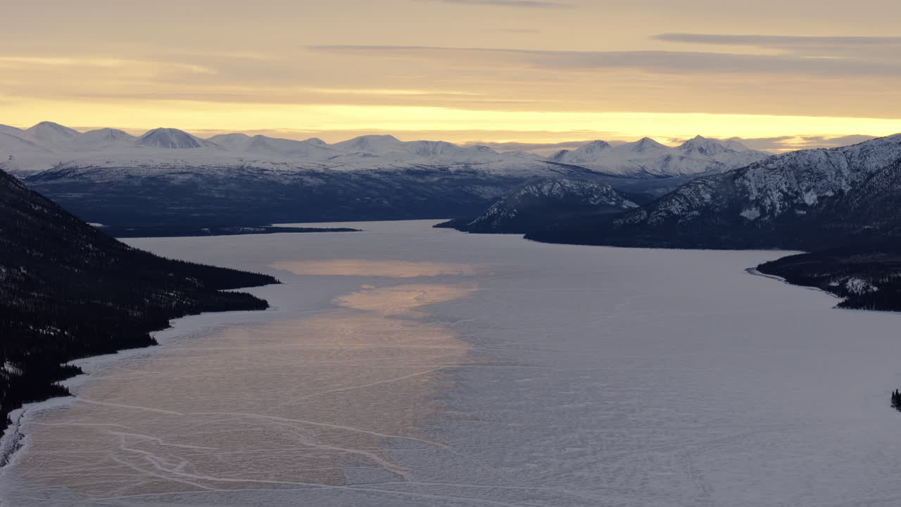 Frozen Kusawa Lake And Snowy Mountain Range In Winter In Yukon, Canada. - aerial wide shot
