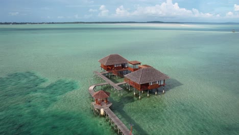 Villas-De-Lujo-Sobre-El-Agua-Conectadas-A-Un-Puente-De-Madera-En-Un-Paisaje-Tropical-En-Un-Día-Soleado