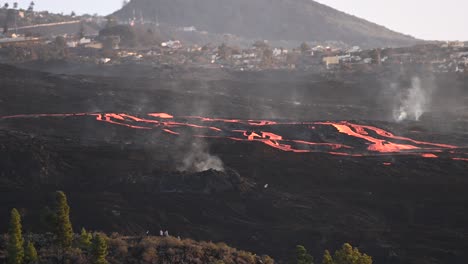 small settlement in mountainous valley with erupting volcano