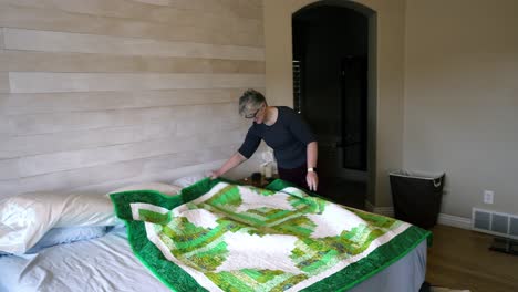 a senior woman, proud of a quilt she made, spreads it out to show her fine work