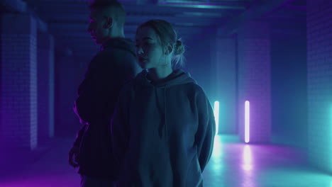 A-duet-of-two-professional-dancers-a-man-and-a-woman.-A-stylish-couple-dances-hip-hop-freestyle-together-in-synchronously-in-lard-lit-in-blue-purple-hues-with-neon-light