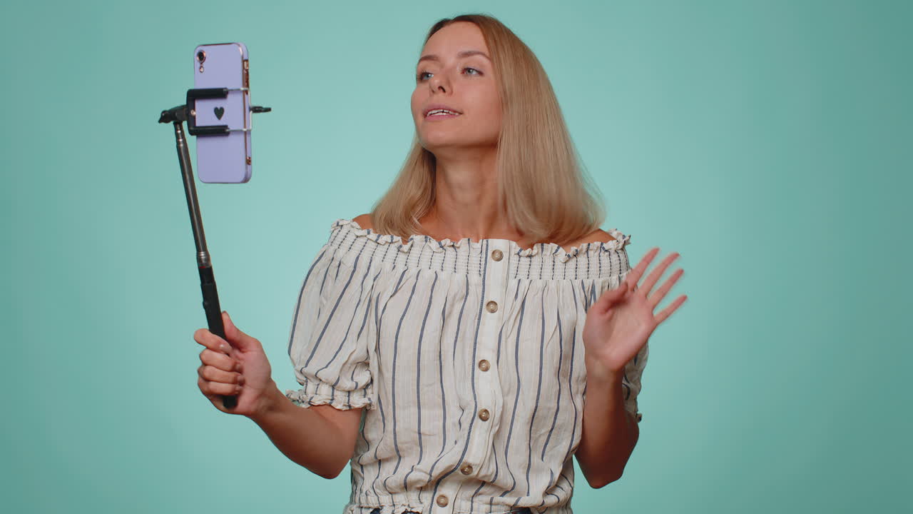 blogger chica tomar selfie en el teléfono móvil selfie stick comunicarse llamada de video en línea con los suscriptores