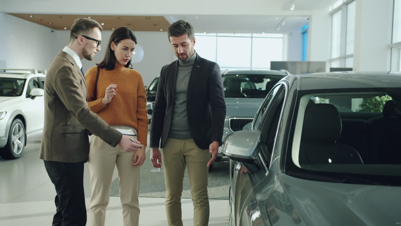 Car Salesman Guiding Couple Through Car Selection in Showroom