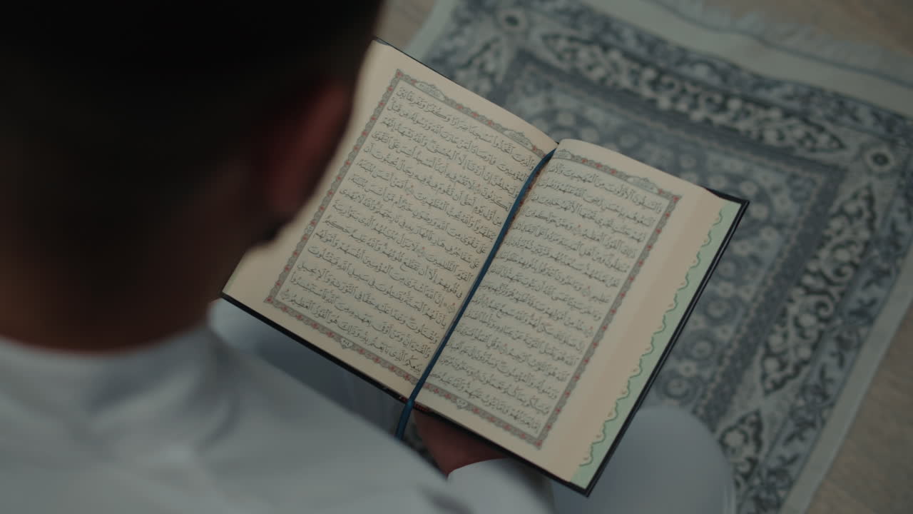 Person reading the Holy Quran on a prayer mat