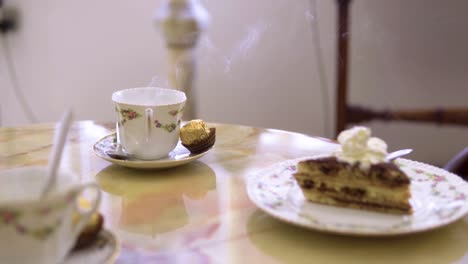 freshly prepared cup of coffee with a lot of smoke coming out of it served with cake cream on top slow motion