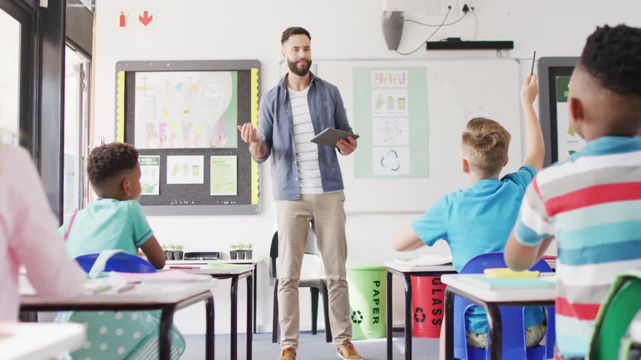 maestro masculino diverso y escolares felices en el escritorio en el aula de la escuela