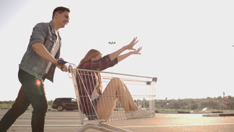 young friends having fun on shopping trolleys. multiethnic young people racing on shopping cart. slow motion