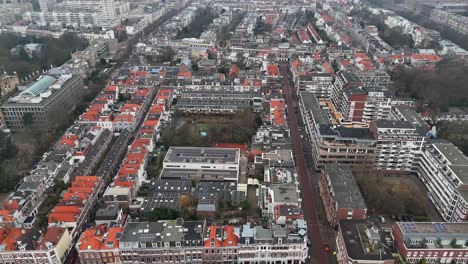 dense row of homes and park with playground in center. solar panels on roof of houses in dutch neighborhood. cold winter day in the hague town, netherlands. aerial flyover shot.