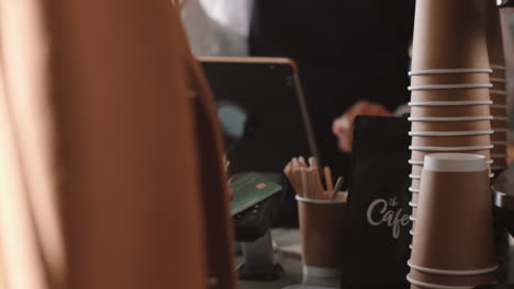 happy barista woman serving customer paying using credit card contactless payment spending money buying coffee in cafe