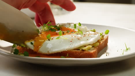 hand carefully cutting sunny-side up egg on avocado toast