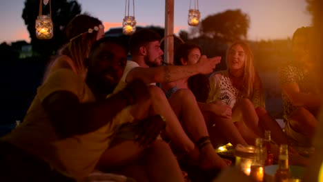 young multi-ethnic friends talking and relaxing at summer beach party