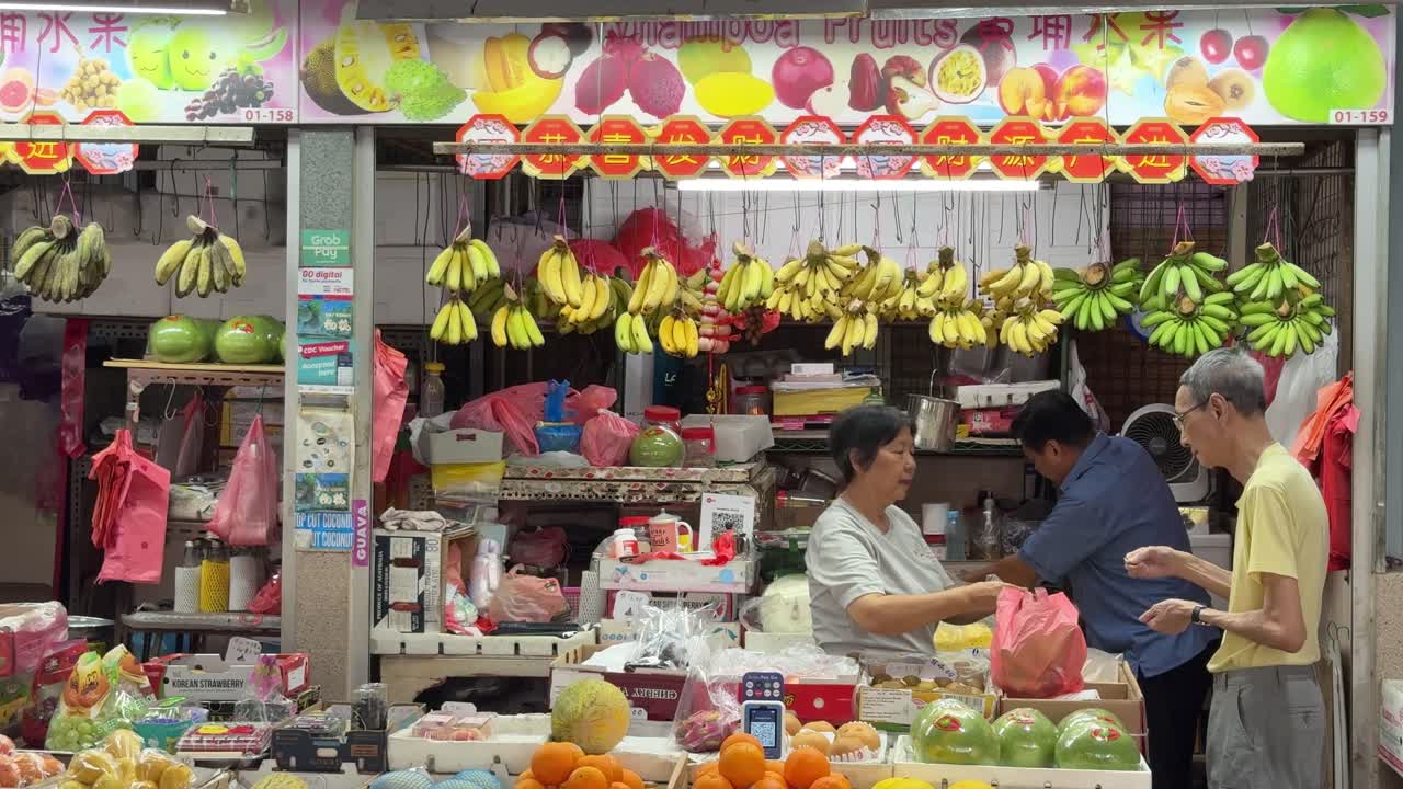 Fruit vendors sell fruits and give change to customers in Whampoa Wet Market, Singapore.