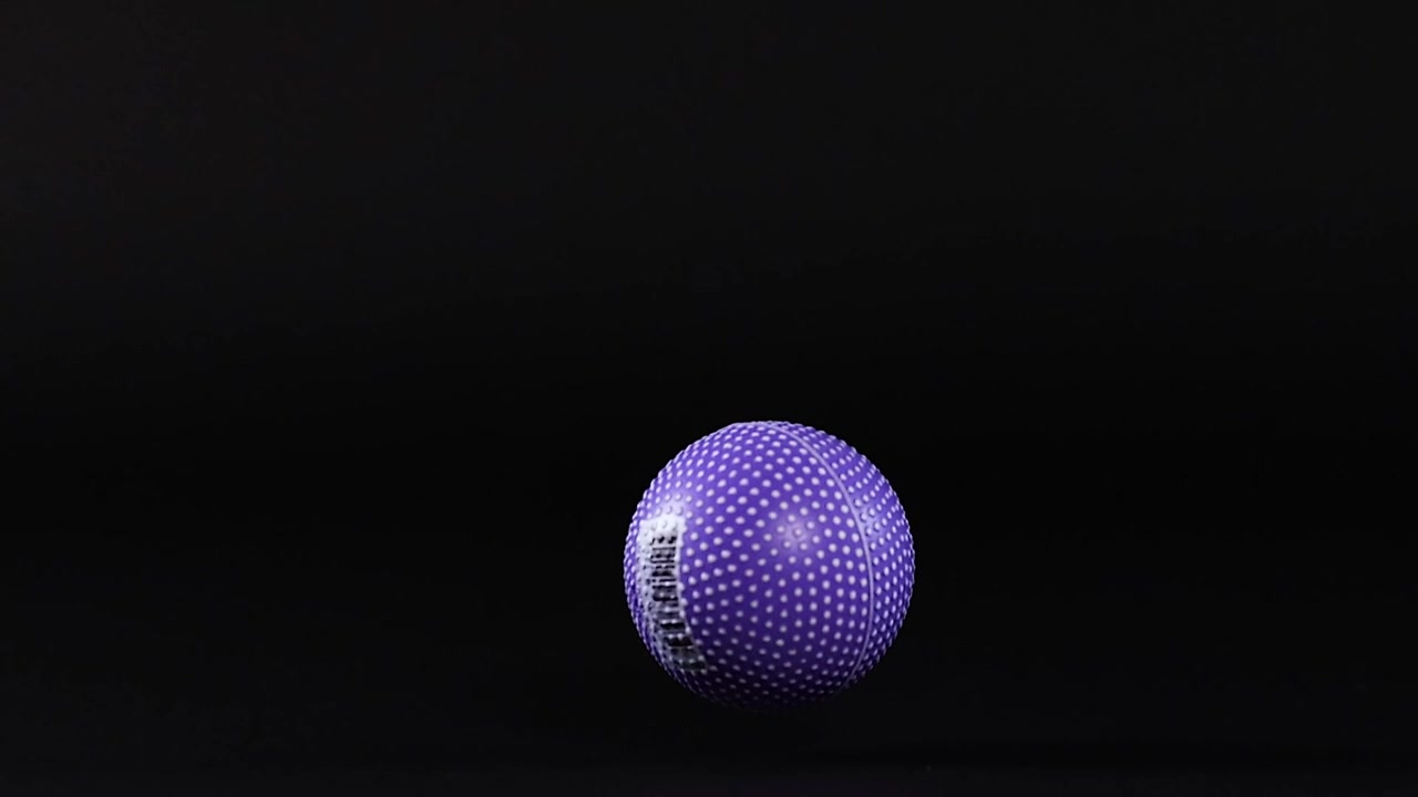 A vibrant purple textured ball bounces and moves across a dark, minimalist studio setting