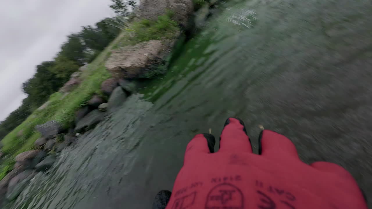 작업 장갑 을 착용 한 사람 이 호수 물 에서 쓰레기 를 던지고 있다, pov view