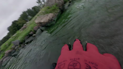 person wearing working gloves throwing out rubbish out of lake water, pov view