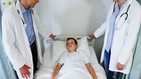 Doctors-interacting-with-a-boy-on-medical-bed