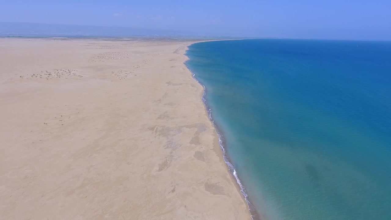 Luftfoto af en stor ørkenstrand, der møder det blå ocean