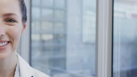 Half-portrait-of-happy-caucasian-female-doctor-smiling-in-hospital,-in-slow-motion-with-copy-space