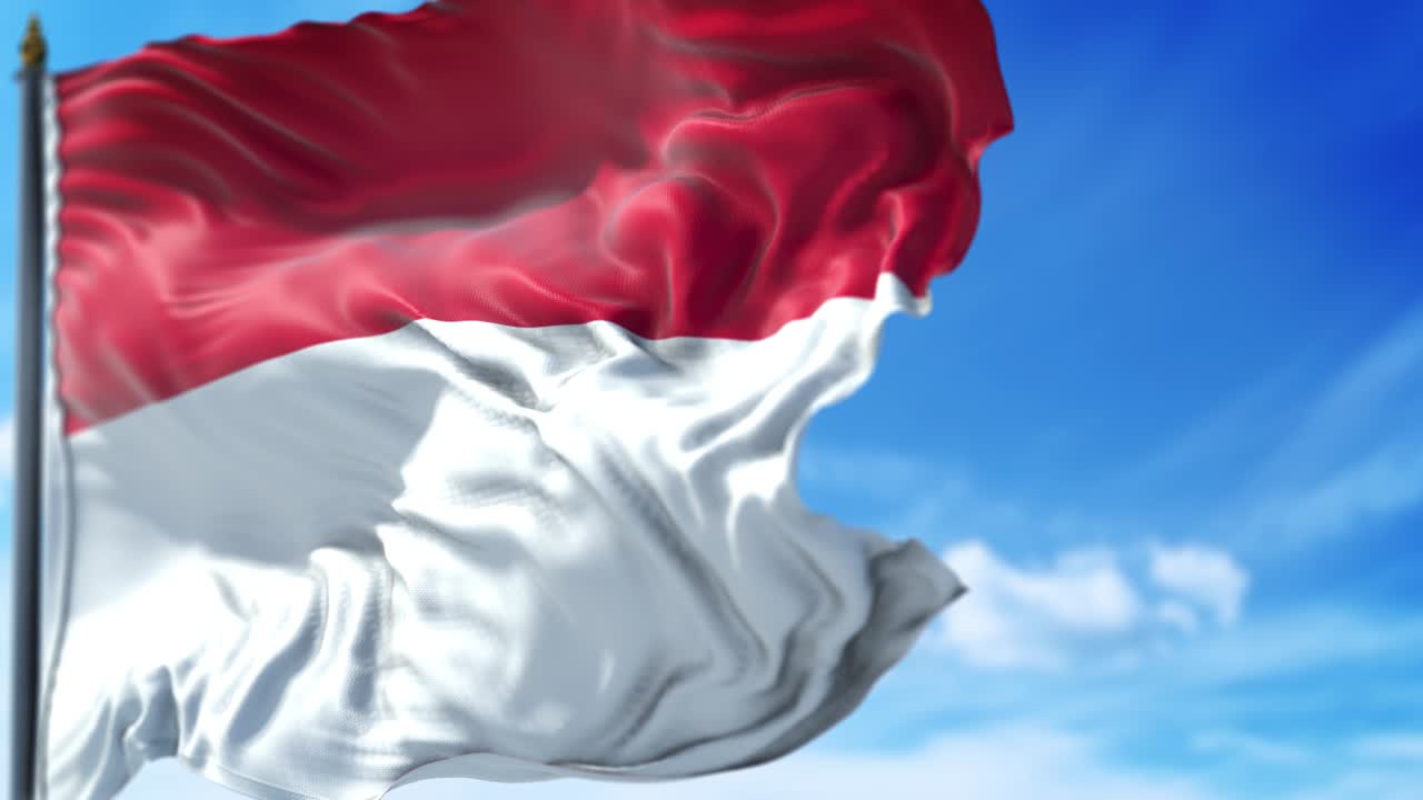 la bandera de mónaco está ondeando lentamente contra el cielo azul.