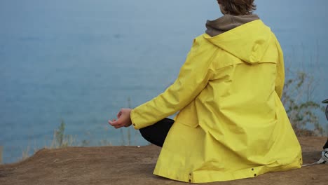 meditating tourist backpacker feel freedom and achievement, sitting on the cliff