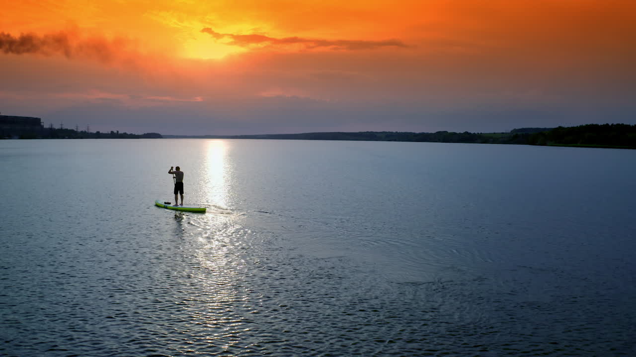 Stand up paddle boarding. Handsome young man standing on sup board