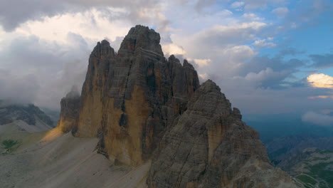 Aerial-view-orbiting-Tre-Cime-mountain-range-rock-formation-peaks-against-blue-sky-mountain-landscape